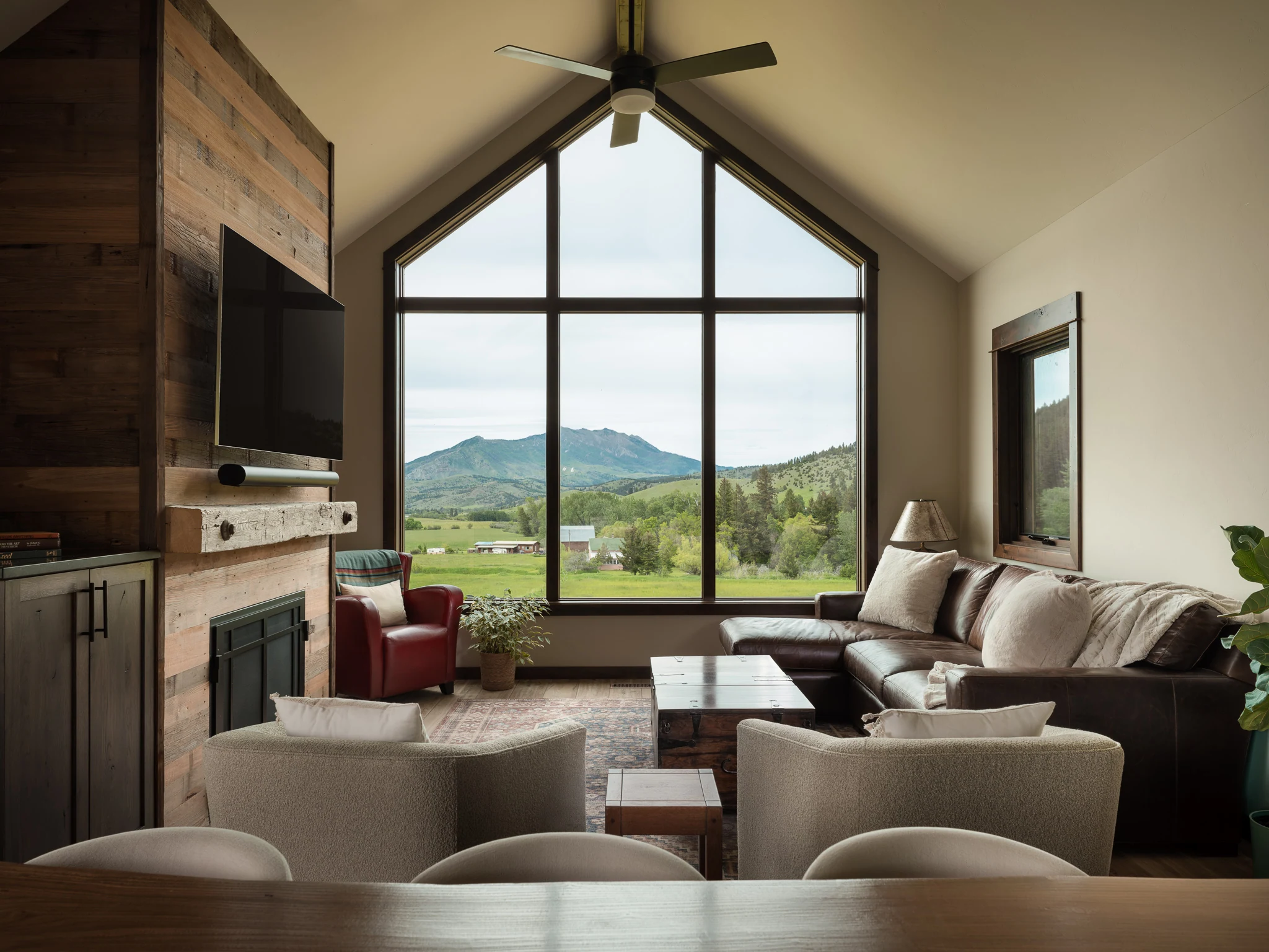 Living room with a vaulted gable window framing mountain views — architectural photography Livingston Montana, Sam Schlauch Designs
